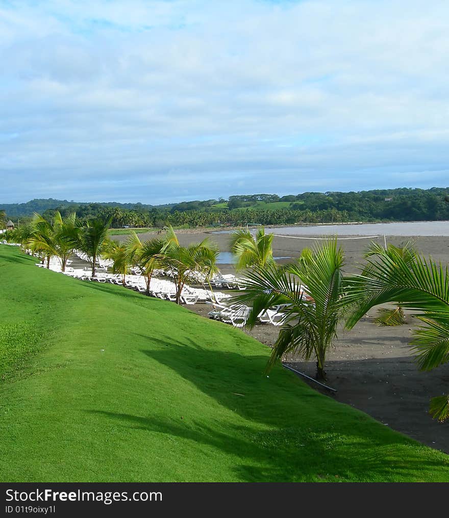 Tropical volcanic dark sand beach and grassy knoll at resort in Costa Rica