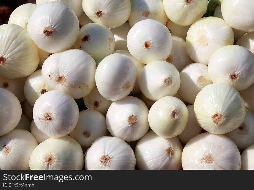 A bunch of fresh peeled white onions on display at the local farmer's market