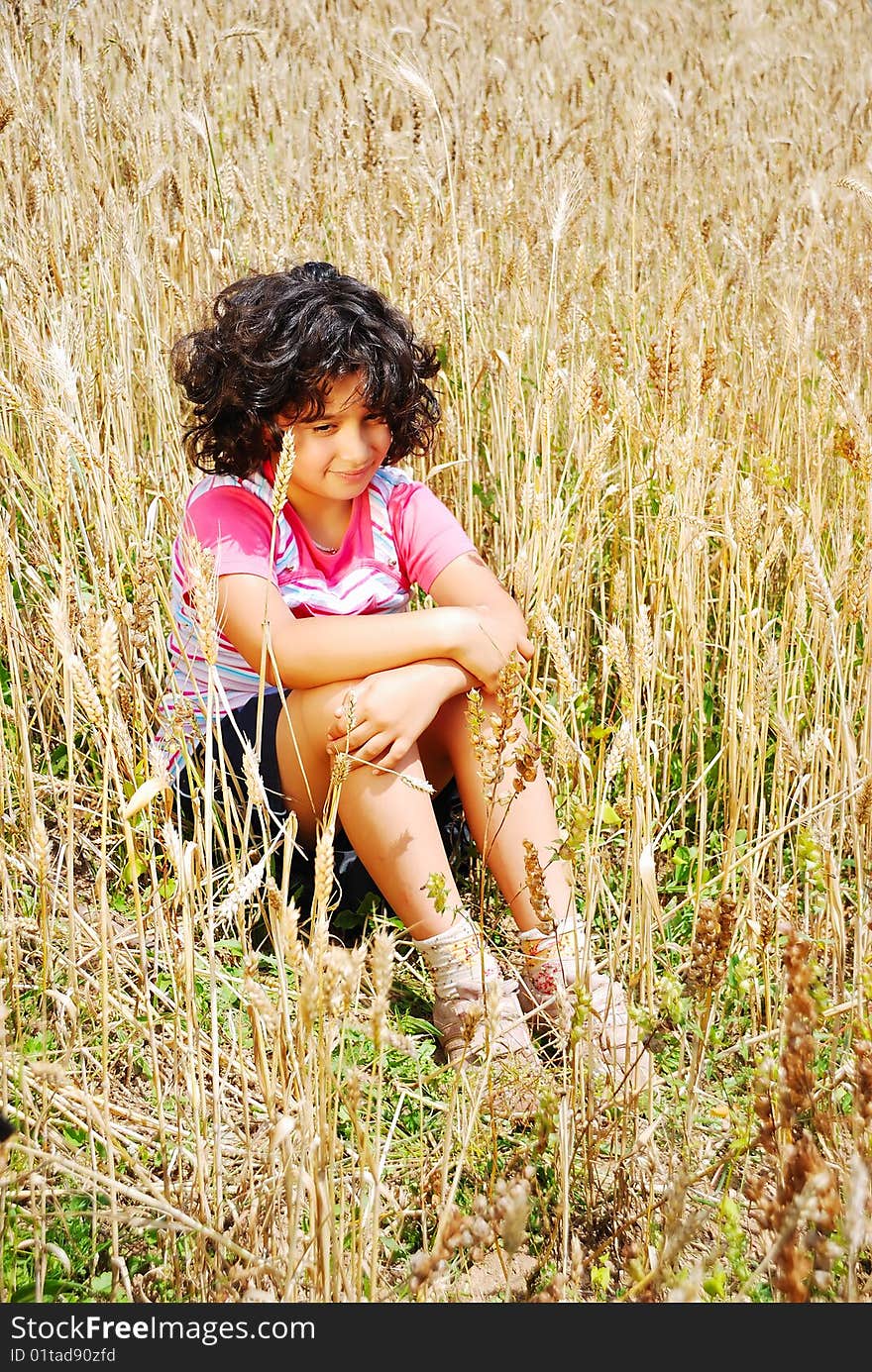 little pretty girl siting on wheat field