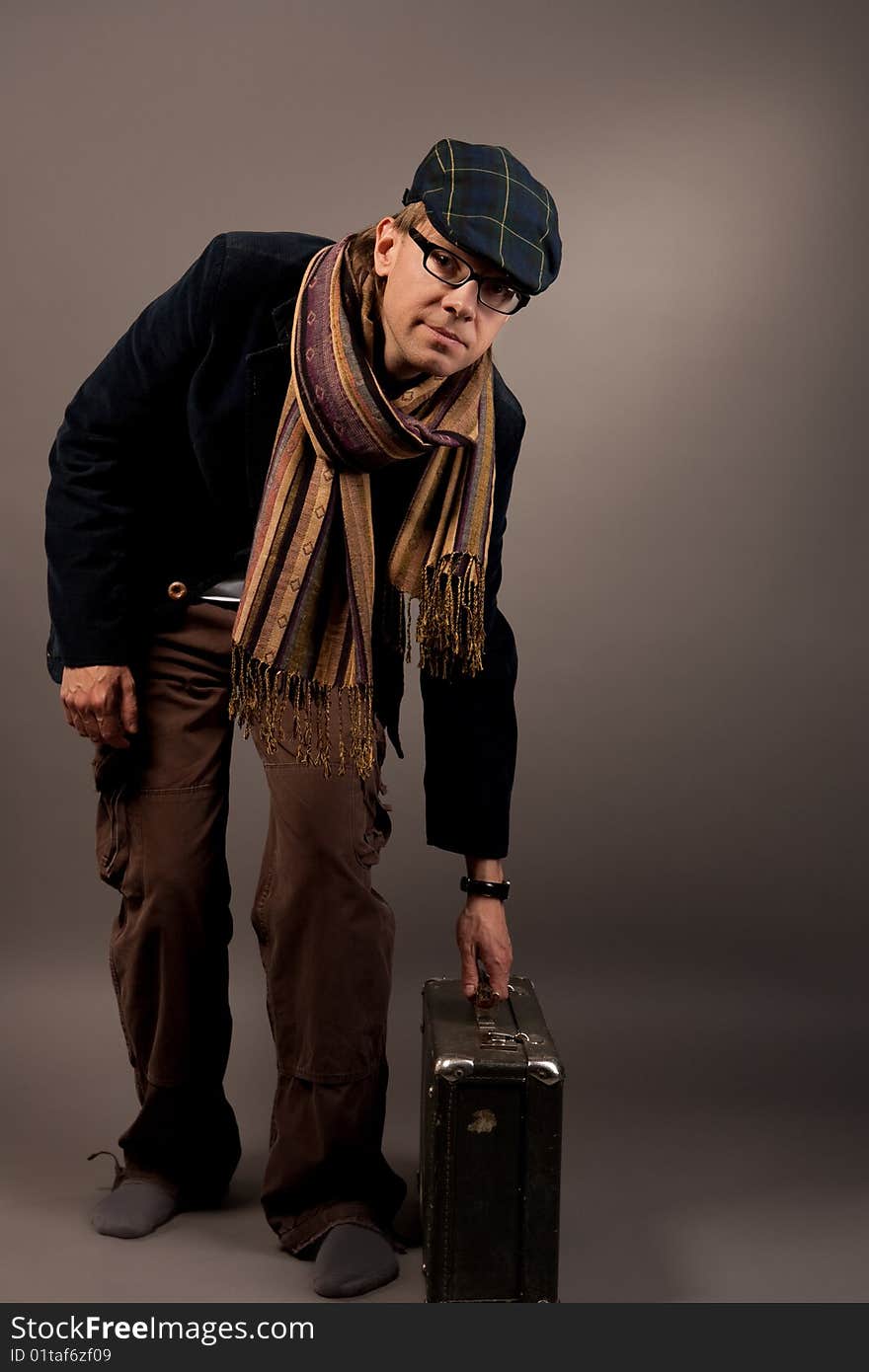 Man in cap with suitcase isolated over gray