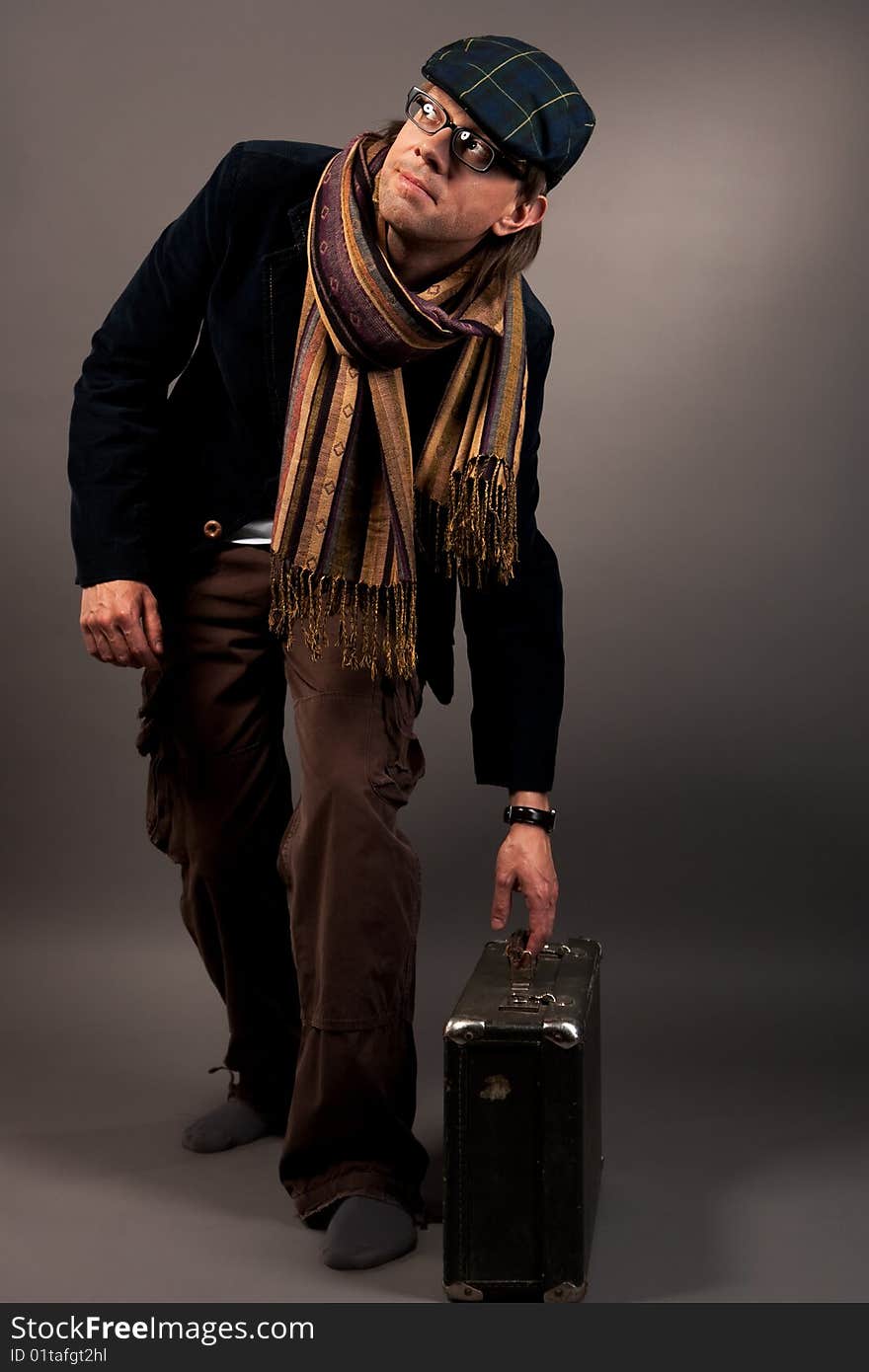 Young man in cap looking up with suitcase separated