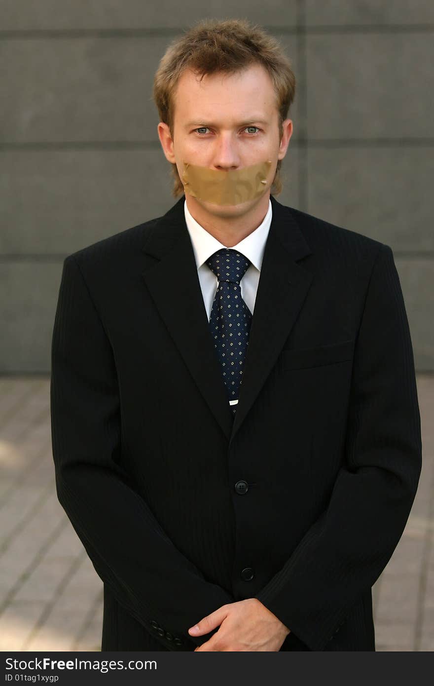 Businessman with adhesive on his Mouth on the street