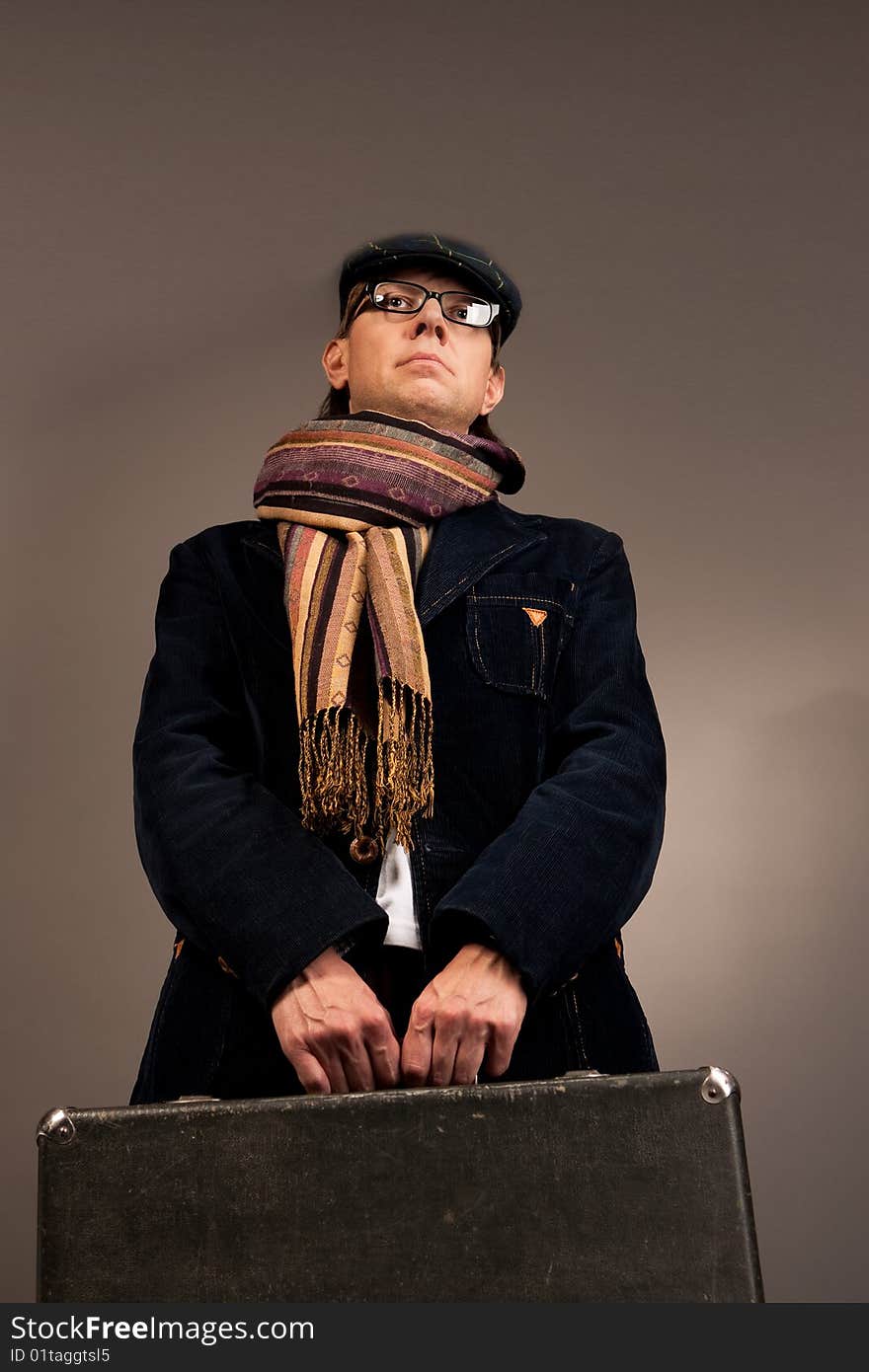 Young man with suitcase in glasses separated over gray