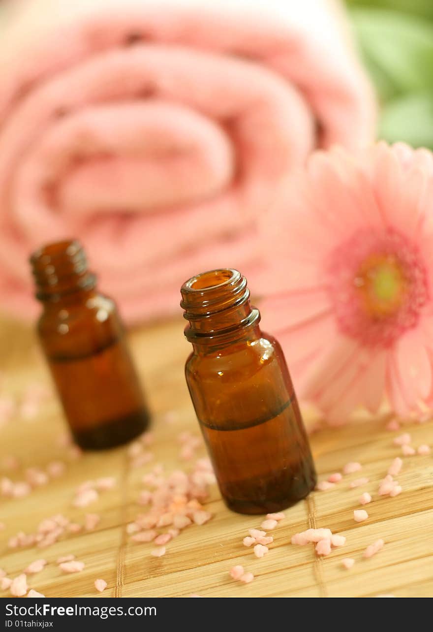 Two bottles of massage oil, towel and pink gerber.