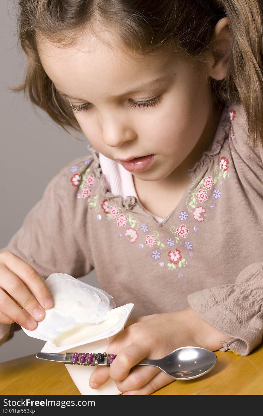 Little girl eating yogurt with a spoon