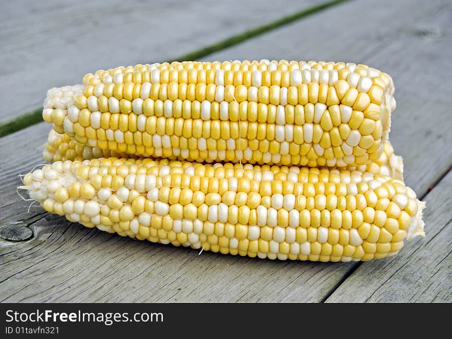 Stacked ears of corn on a weathered table. Stacked ears of corn on a weathered table.