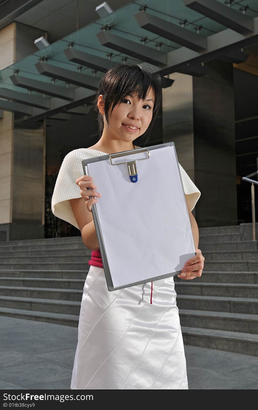 Beautiful young and modern Asian woman in the city showing a clipboard.