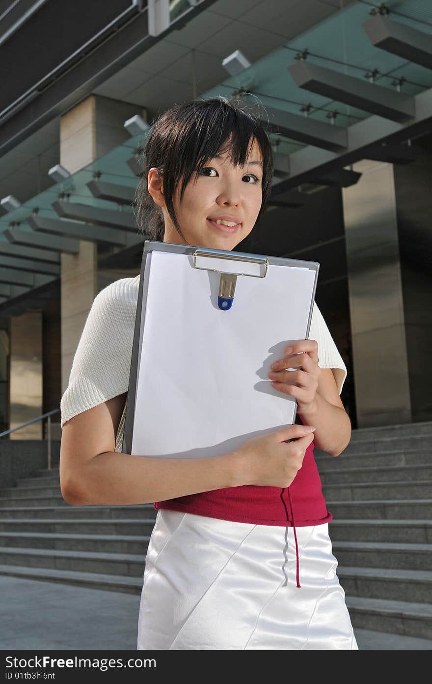 Beautiful young and modern Asian woman in the city showing a clipboard. Beautiful young and modern Asian woman in the city showing a clipboard.