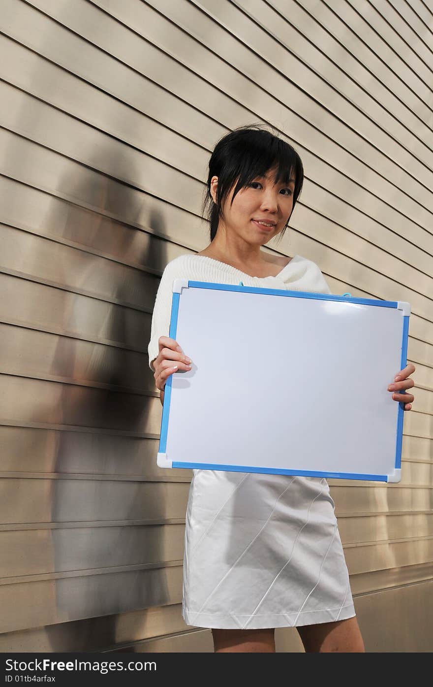 Beautiful young and modern Asian woman in the city showing a clipboard.