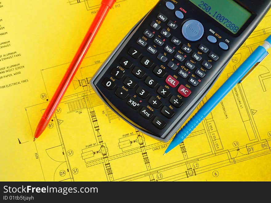 Scientific calculator and pen on yellow plan for a pumping station