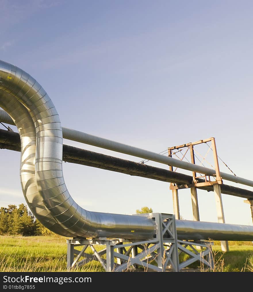 Industrial pipelines on pipe-bridge against blue sky.