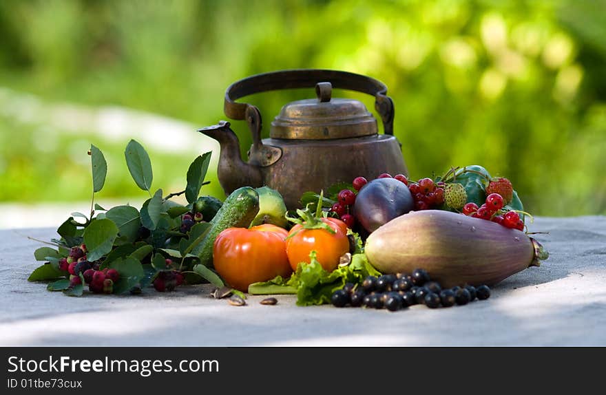 Berries, vegetables and an ancient teapot on a grey cloth. Berries, vegetables and an ancient teapot on a grey cloth