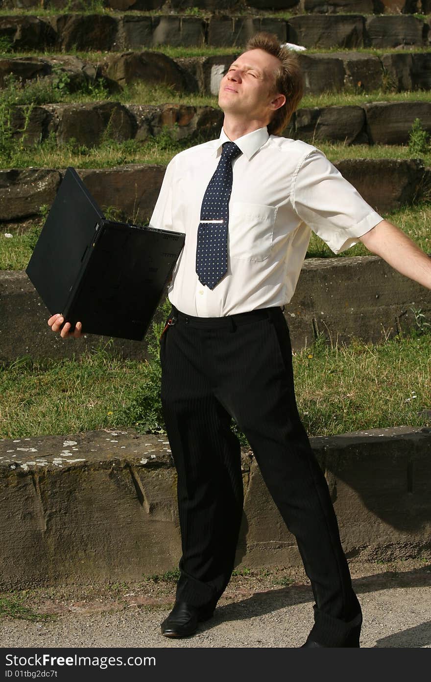 Happy businessman with laptop computer enjoying the sun