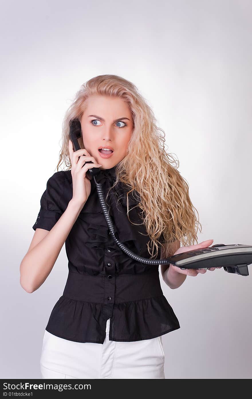 Shocked businesswoman with a phone, closeup studio shot