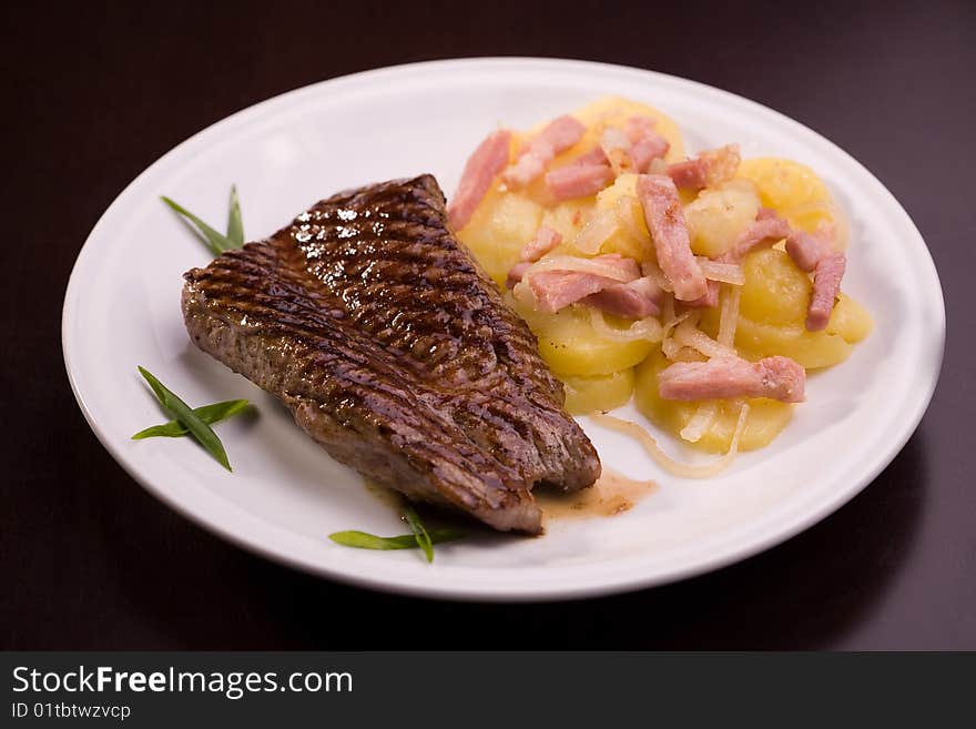 Steak with potatoes isolated on dark background