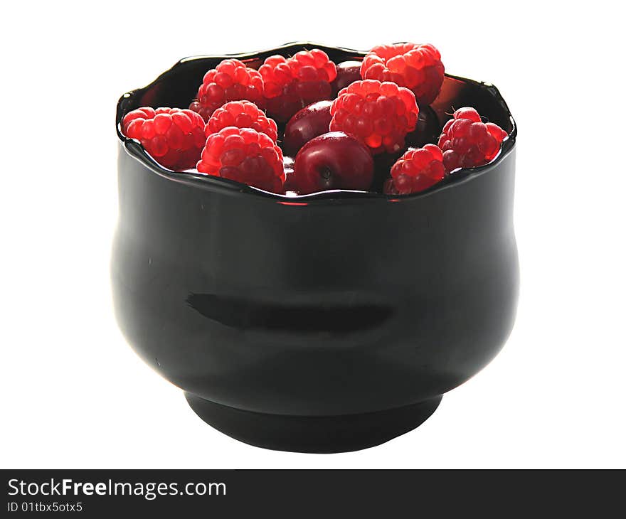 Raspberries and cherry in the black glass bowl, isolated on white. Raspberries and cherry in the black glass bowl, isolated on white