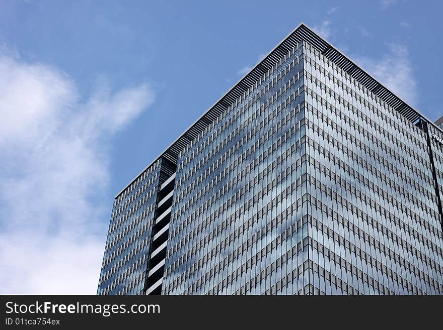 Tall futuristic skyskraper with shining facade in downtown Tokyo, Japan against a blue sky. Tall futuristic skyskraper with shining facade in downtown Tokyo, Japan against a blue sky