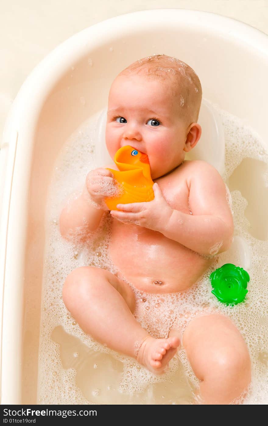 A baby-girl with a rubber-duck in her mouth. A baby-girl with a rubber-duck in her mouth