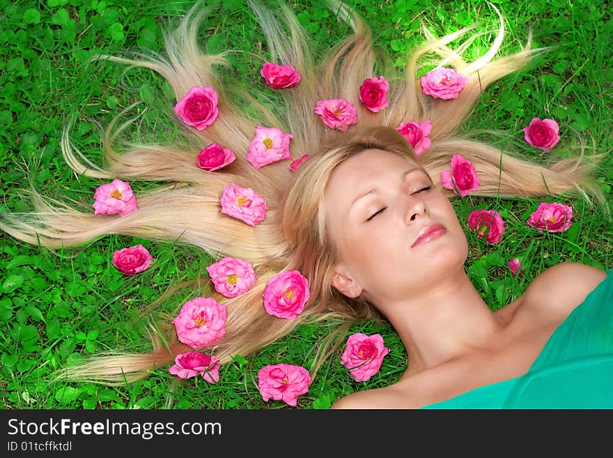 Beautiful woman relax on grass with flower all around head.