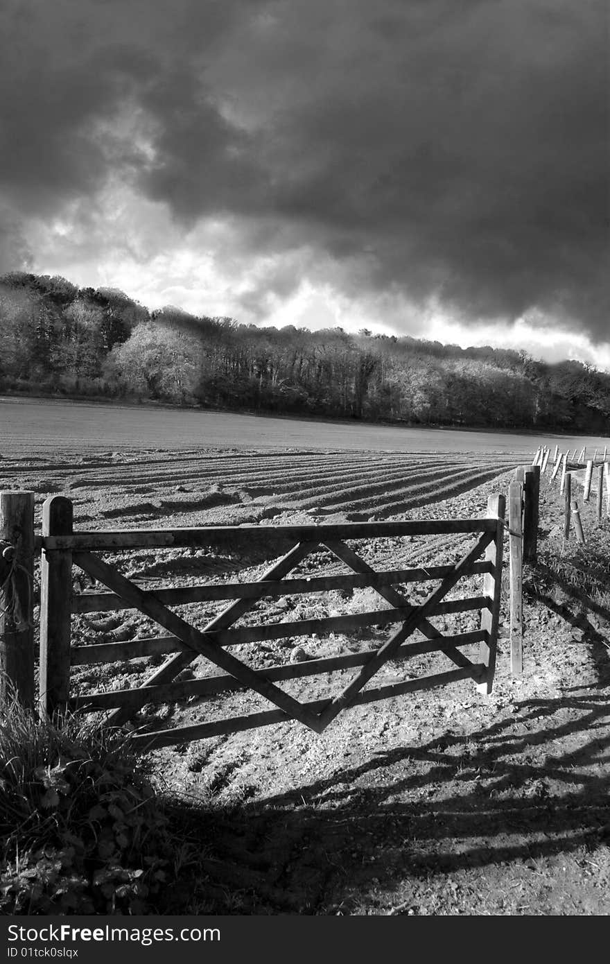 An old gate to ploughed field shadowed by a stormy skyline. An old gate to ploughed field shadowed by a stormy skyline