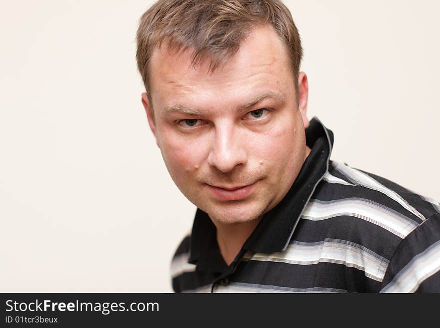 The man poses on a wall background indoor. The man poses on a wall background indoor