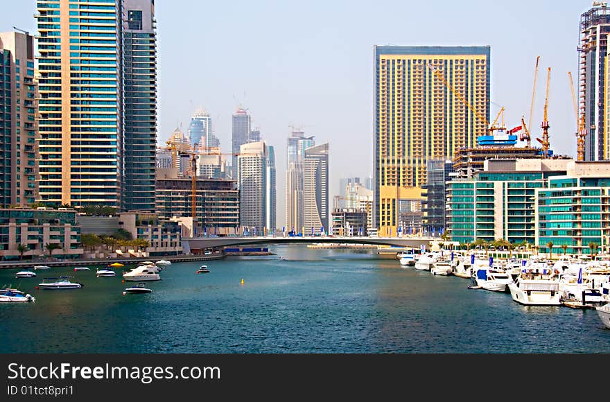 Several boats and yachts berthed in the Dubai Marina with luxury apartments in the background. Several boats and yachts berthed in the Dubai Marina with luxury apartments in the background