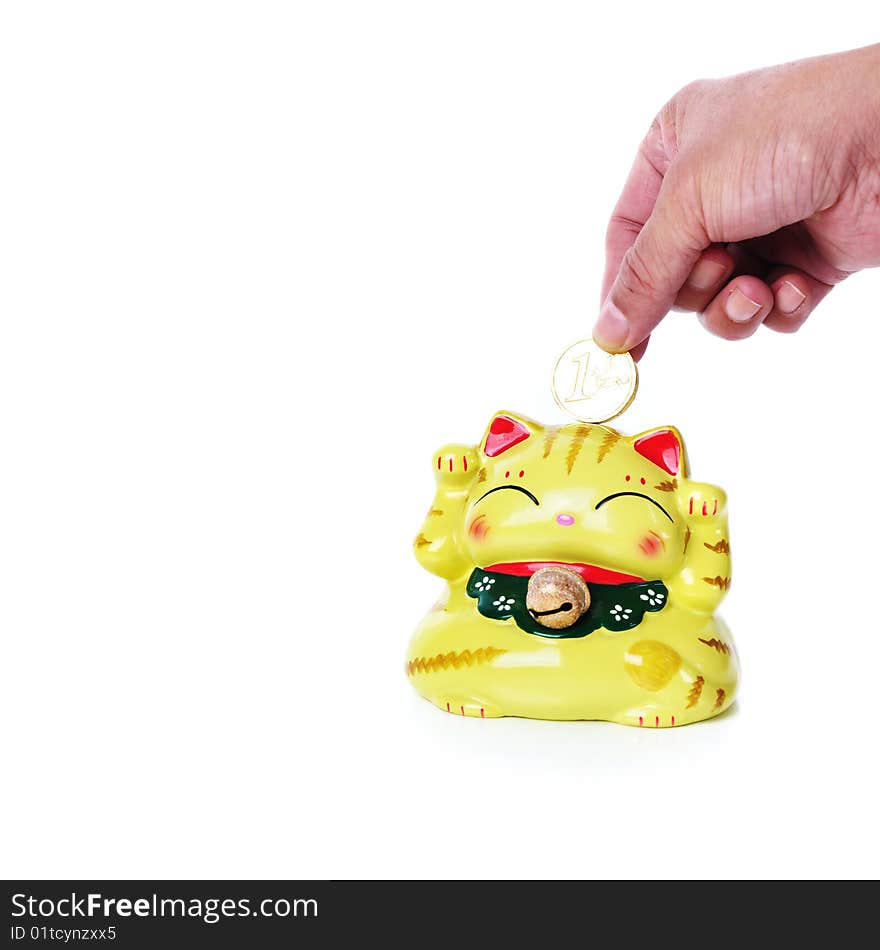 A hand put a gold coin into the box of lucky cat. A hand put a gold coin into the box of lucky cat