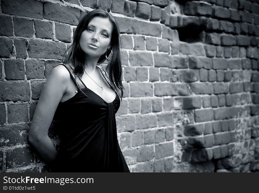 Charming woman in black dress near the wall. Charming woman in black dress near the wall