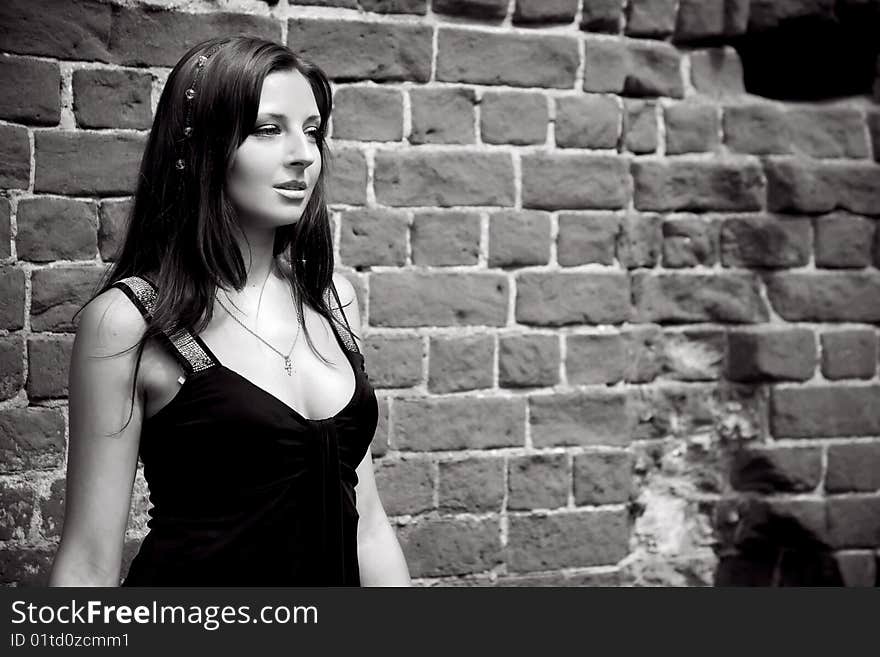 Woman near brick wall in black elegant black dress. Woman near brick wall in black elegant black dress