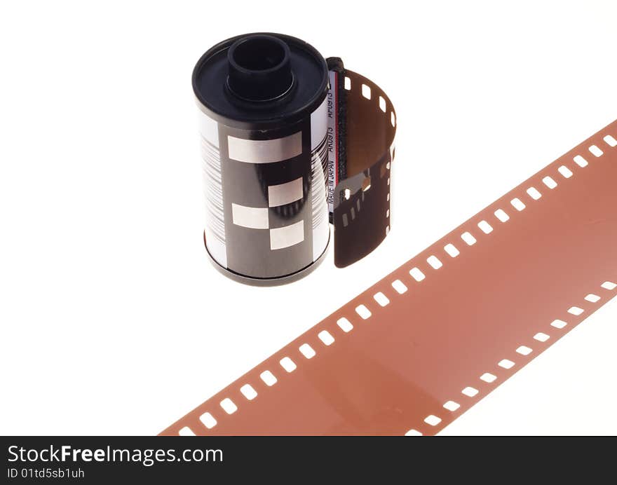 Photographic, 35mm, negative film in container, standing on a white background with a piece of negative film diagonally positioned in front. Photographic, 35mm, negative film in container, standing on a white background with a piece of negative film diagonally positioned in front.