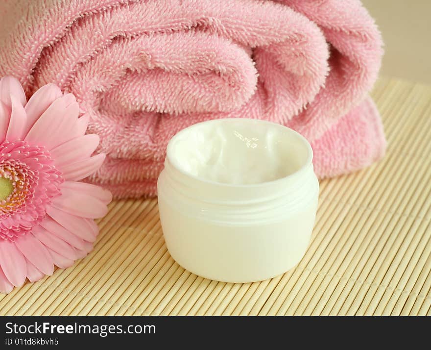 Spa essentials. Bowl of cream, towel and flowers.