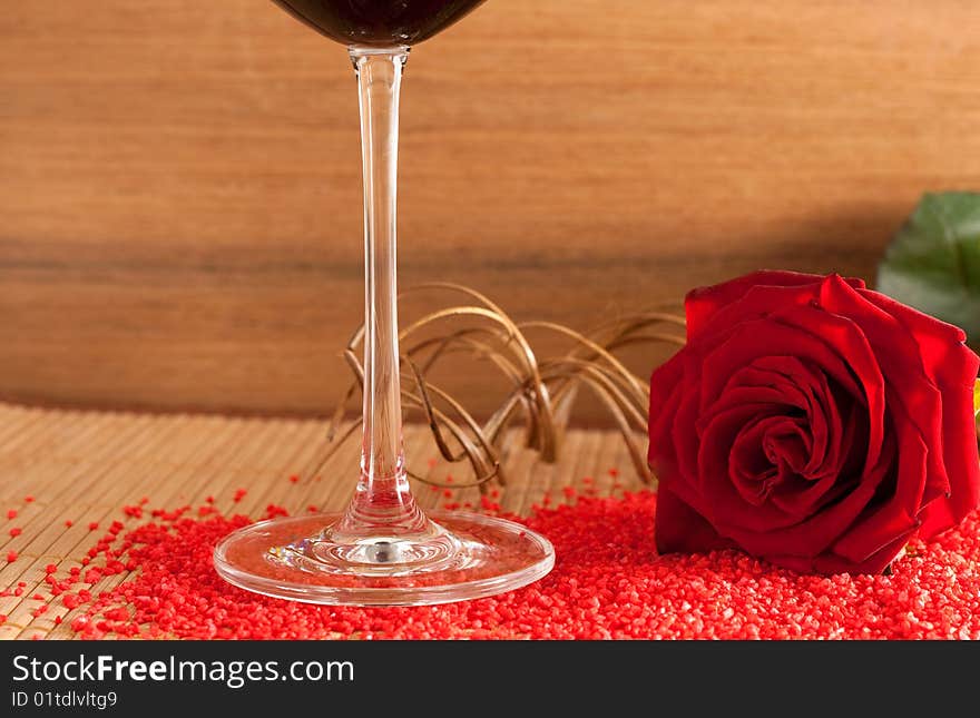 A red rose and a wine glass on a wooden bottom isolated on white background. A red rose and a wine glass on a wooden bottom isolated on white background