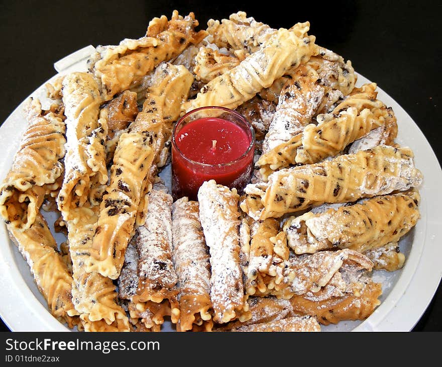 Plate of rolled pizzelles sprinkled with powdered sugar.