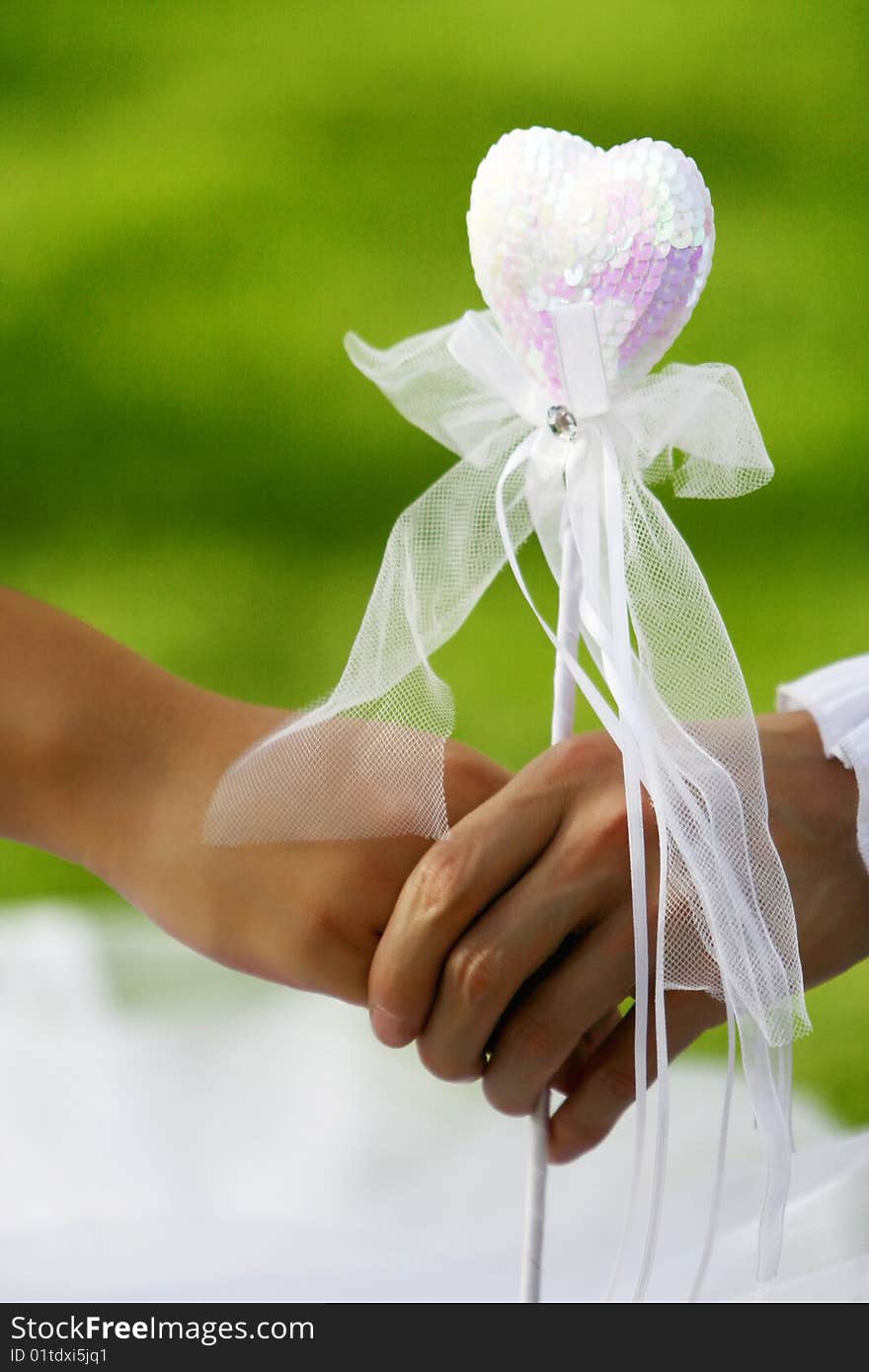 Couple's hands holding a pink heart-shaped property. Couple's hands holding a pink heart-shaped property