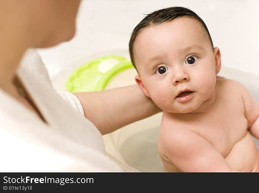 Baby boy in a bathtube held by his mother. Baby boy in a bathtube held by his mother