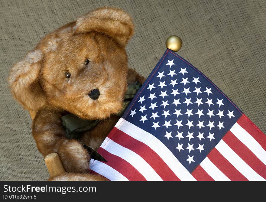 A cute little toy stuffed brown bear holding an American flag, shallow depth of field, horizontal with copy space. A cute little toy stuffed brown bear holding an American flag, shallow depth of field, horizontal with copy space