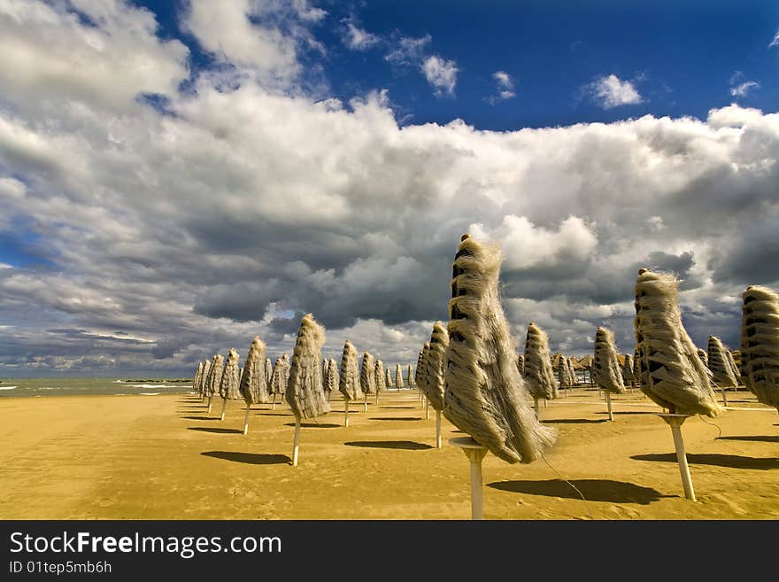 Windy day in late summer in an Italian beach with umbrellas and people without