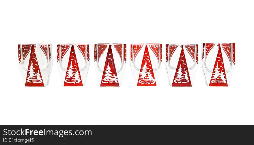 Row of beautiful red crystal liqueur glasses with cut fir-tree isolated. Row of beautiful red crystal liqueur glasses with cut fir-tree isolated