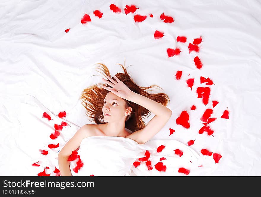 Beautiful girl in bed with red plumage