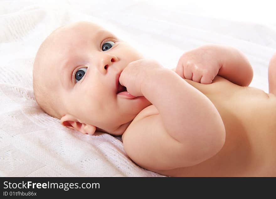 Cute baby boy on white blanket, close-up