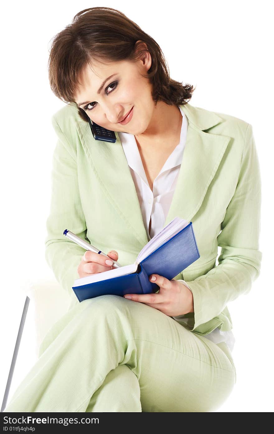 Businesswoman on white background using cell phone writing in notebook. Businesswoman on white background using cell phone writing in notebook