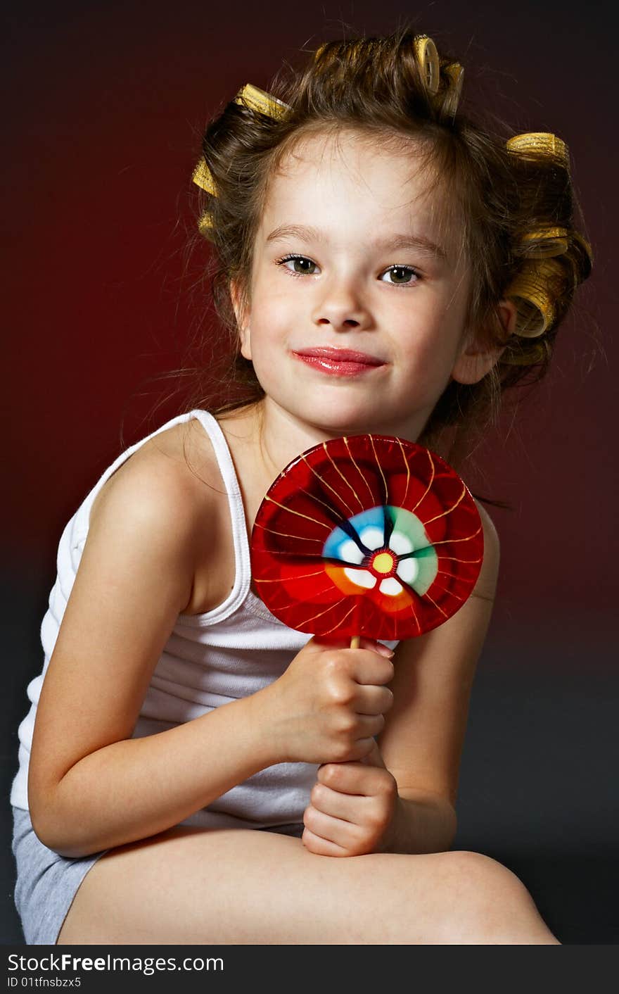 Portrait of little curly girl with lollipop