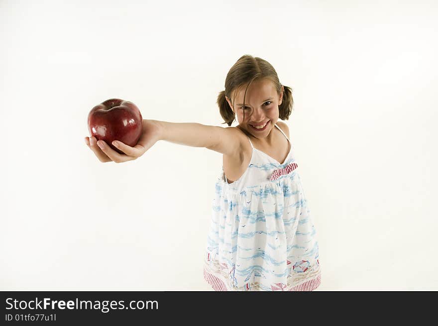 A young girl holding out an apple isolated on white. A young girl holding out an apple isolated on white