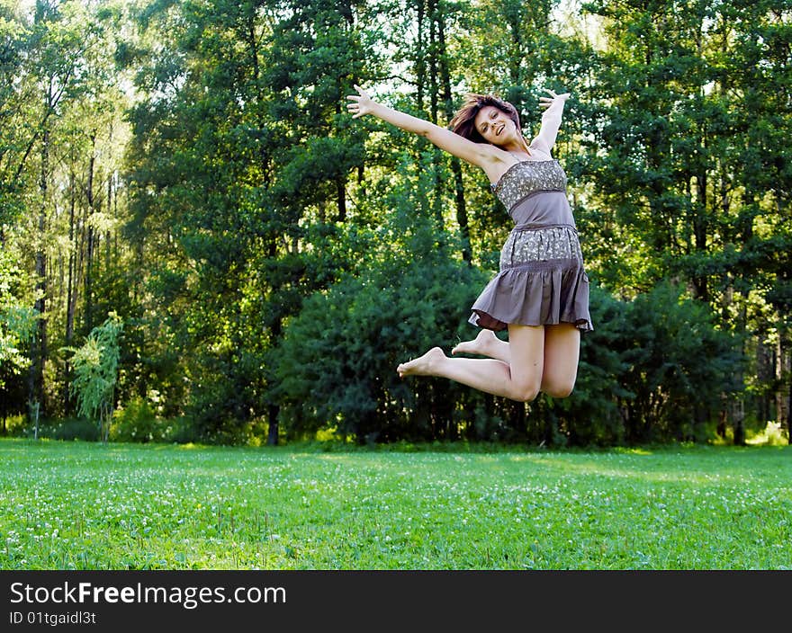 Smiling beautiful happy girl jumping in a park in summer. Smiling beautiful happy girl jumping in a park in summer