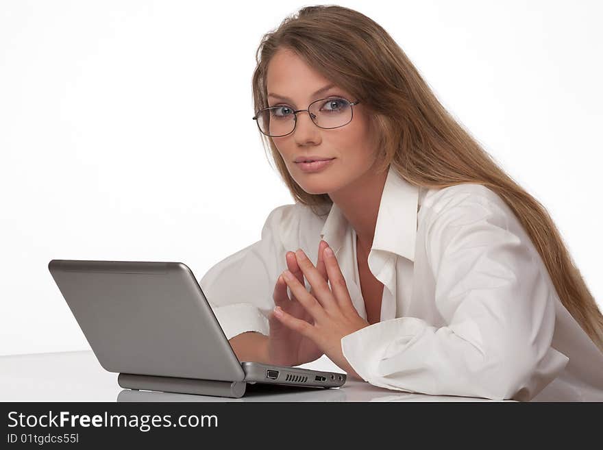 The modern young woman in points, sits at a table with the personal computer, and looks in the chamber. The modern young woman in points, sits at a table with the personal computer, and looks in the chamber