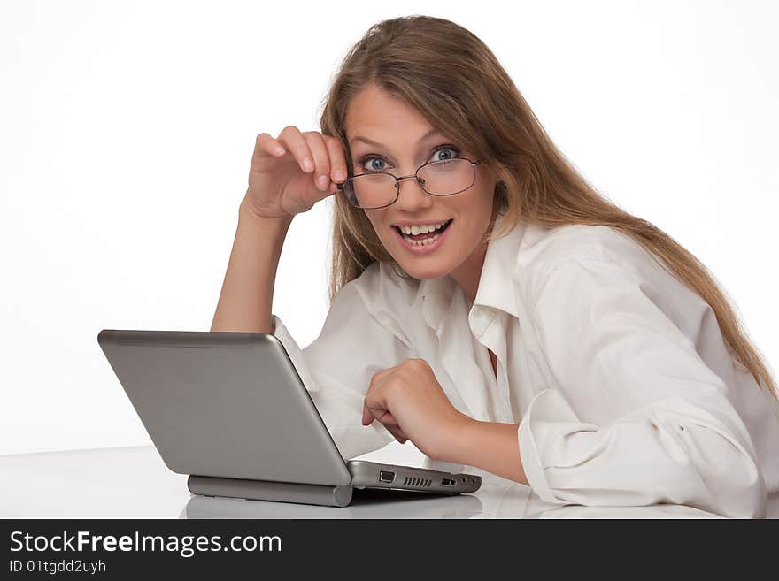 The modern young woman sits at a table with the personal computer, holds points in a hand and looks in the chamber. The modern young woman sits at a table with the personal computer, holds points in a hand and looks in the chamber