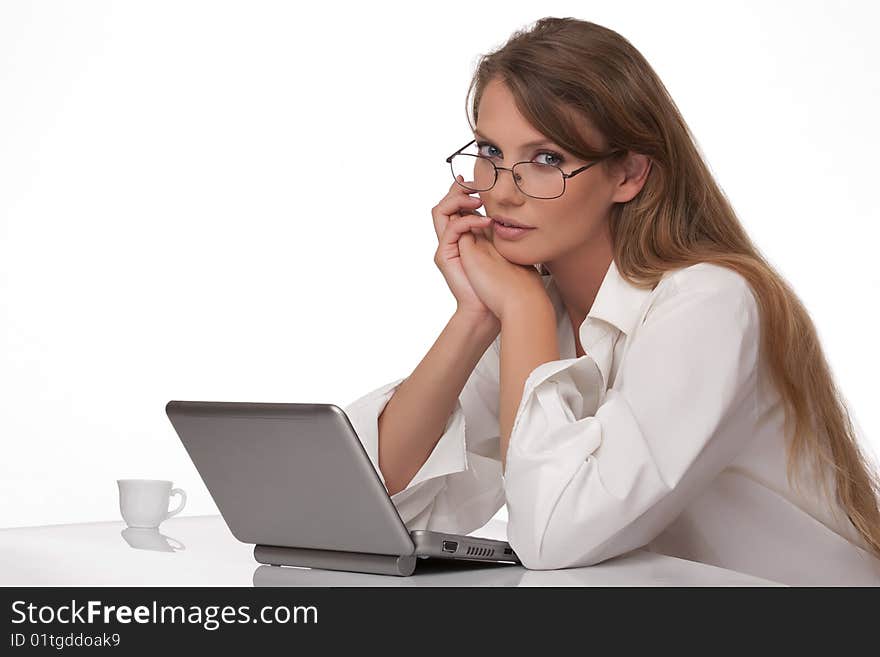 The modern young woman in points, sits at a table with the personal computer, and looks in the chamber. The modern young woman in points, sits at a table with the personal computer, and looks in the chamber