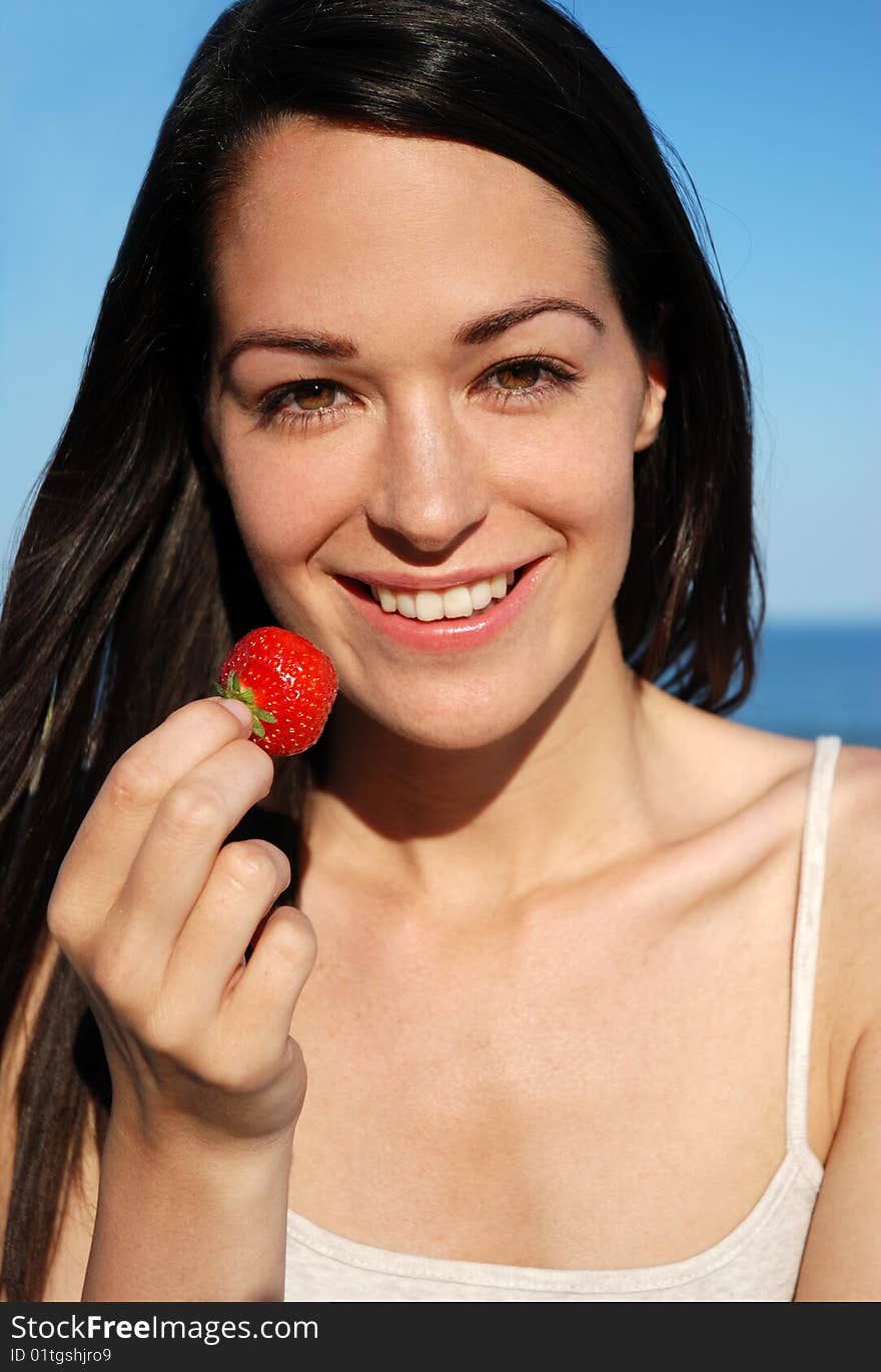 Woman eating fresh strawberry in the sun. Woman eating fresh strawberry in the sun