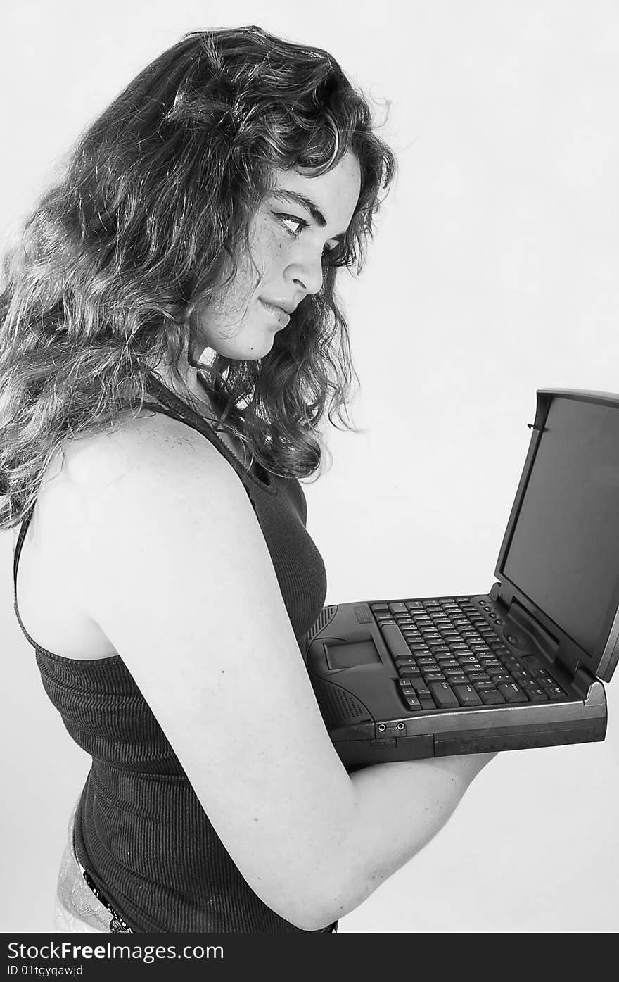 A black and white photo of an young woman holding an laptop in her hand and is concentrated on the screen, with long curly hair. A black and white photo of an young woman holding an laptop in her hand and is concentrated on the screen, with long curly hair.