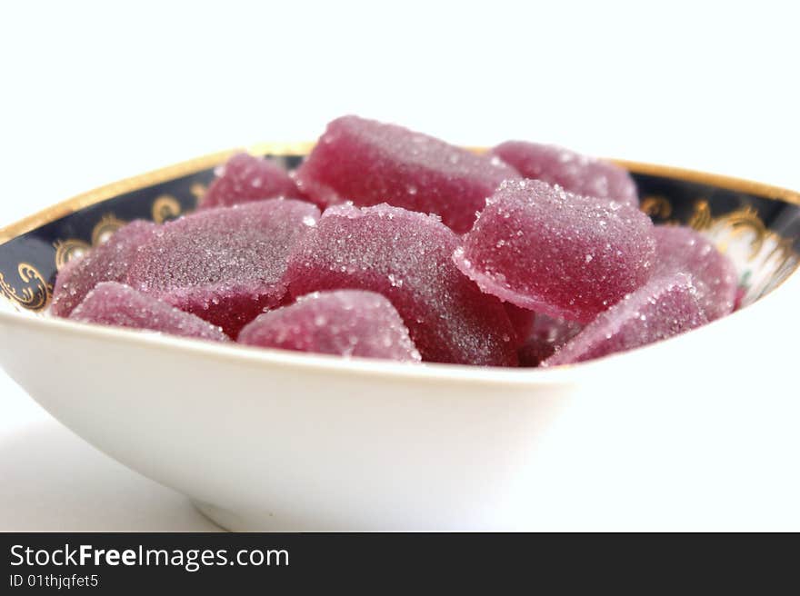 Fruit candy in a square plate with patterns on a white background